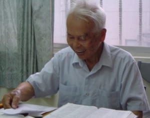 Elder Liau reviewing a draft translation of the Hakka Bible.