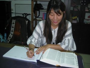 A young Ngudradrekai woman writing out the Bible by hand