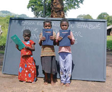 Three students from Chabwe School in Mozambique stand in front of their new blackboard - made possible through fundraising at First Church, Penetanguishene, Ont. The small rural school was in desperate need of supplies and renovations.