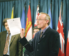 Joe Gunn, of KAIROS, holds up a petition at a news conference on Parliament Hill that calls on the federal government to immediately implement the Refugee Appeal Division. Refugee rights groups say the government has delayed the process for three years. Photo - Art Babych