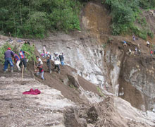 Rain washed away many roads making access to remote areas very difficult. Here pedestrians are trying to cross a cliff face where there once was a road.