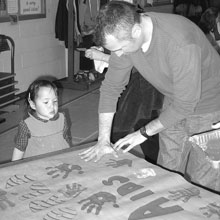 Christopher Walker helps a young missionary make a poster for Towards A World Without AIDS project.