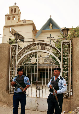 Iraqi policemen stand guard outside a church in Baghdad, Iraq. Photo by Karim Kadim / CP Images
