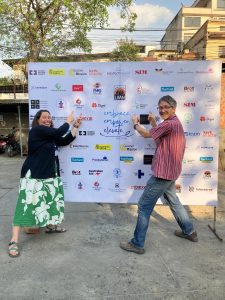 Lora and Mitch in front of logo board